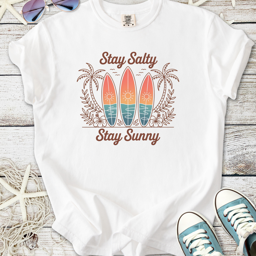 White t-shirt with 'Stay Salty Stay Sunny' graphic, featuring surfboards and palm trees design.