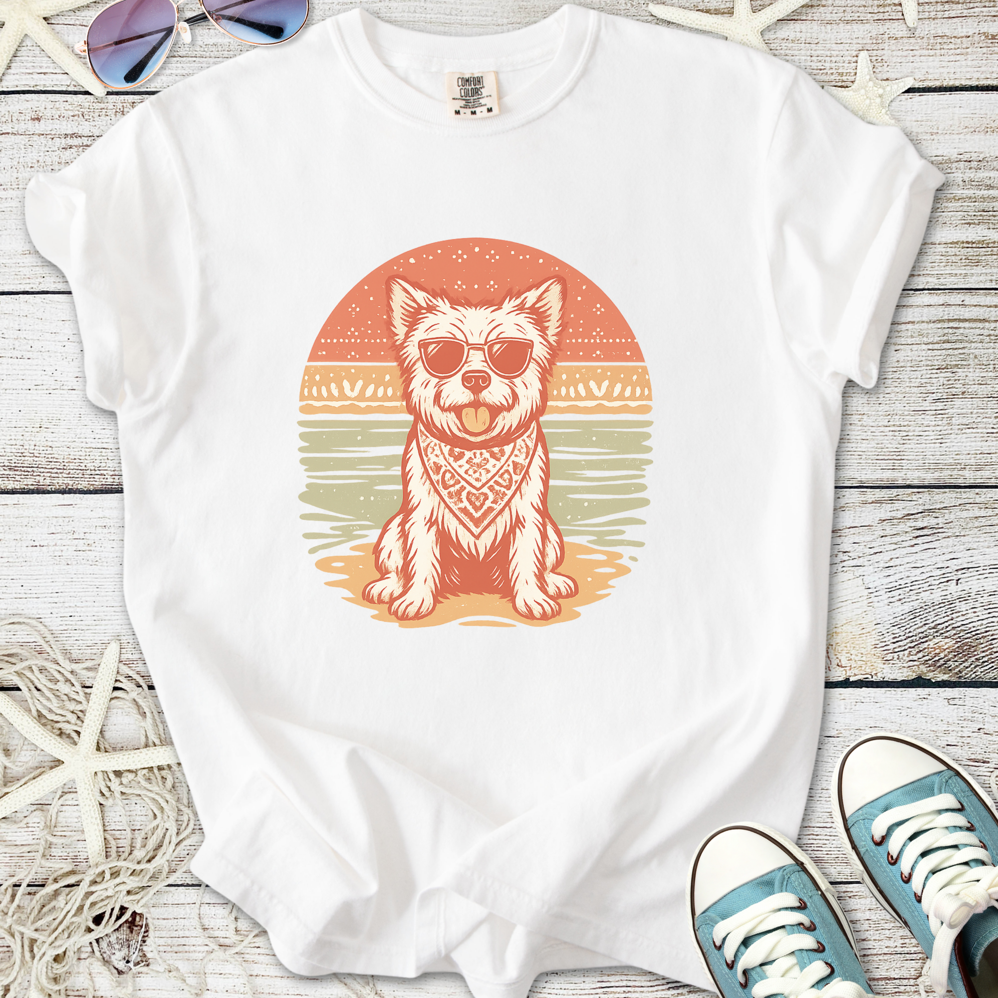 White t-shirt featuring a dog in sunglasses and a bandana, beach sunset graphic design.