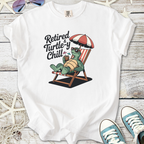 White t-shirt with quirky turtle graphic saying 'Retired & Turtle-y Chill' for a fun, relaxed style.