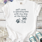 White t-shirt with 'self care is spending time with my dog at the beach' design and beach-themed graphics.
