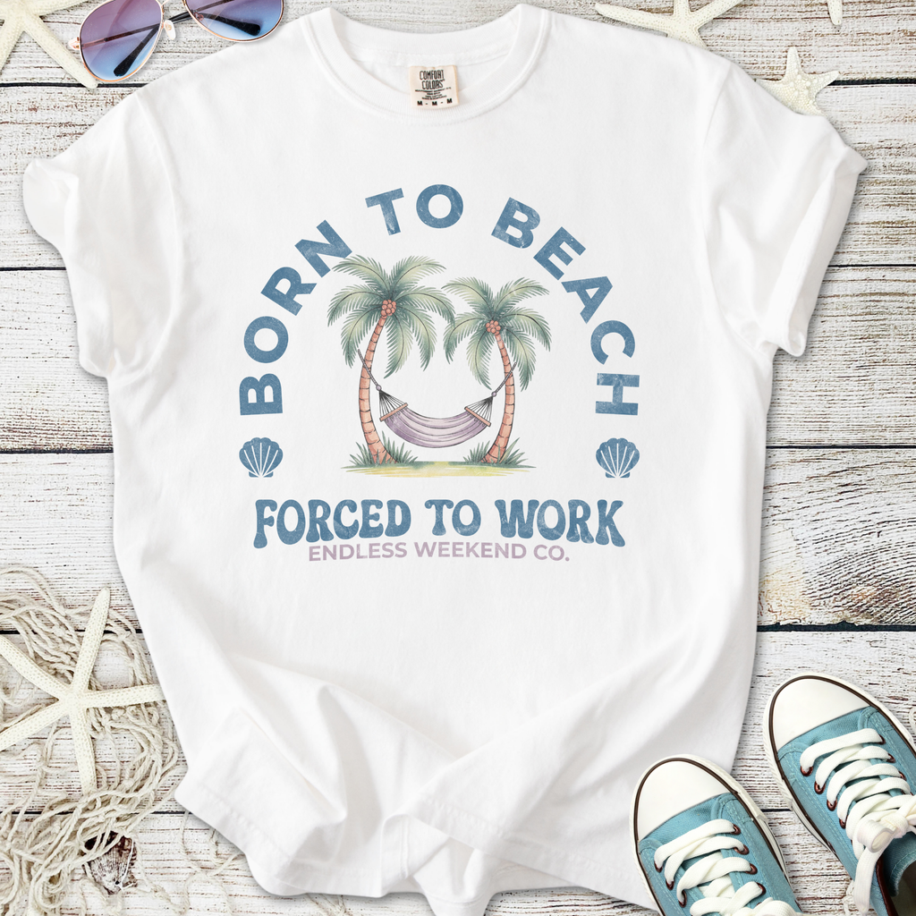 White t-shirt with 'Born to Beach' graphic, featuring palm trees and a hammock, perfect for summer wear.