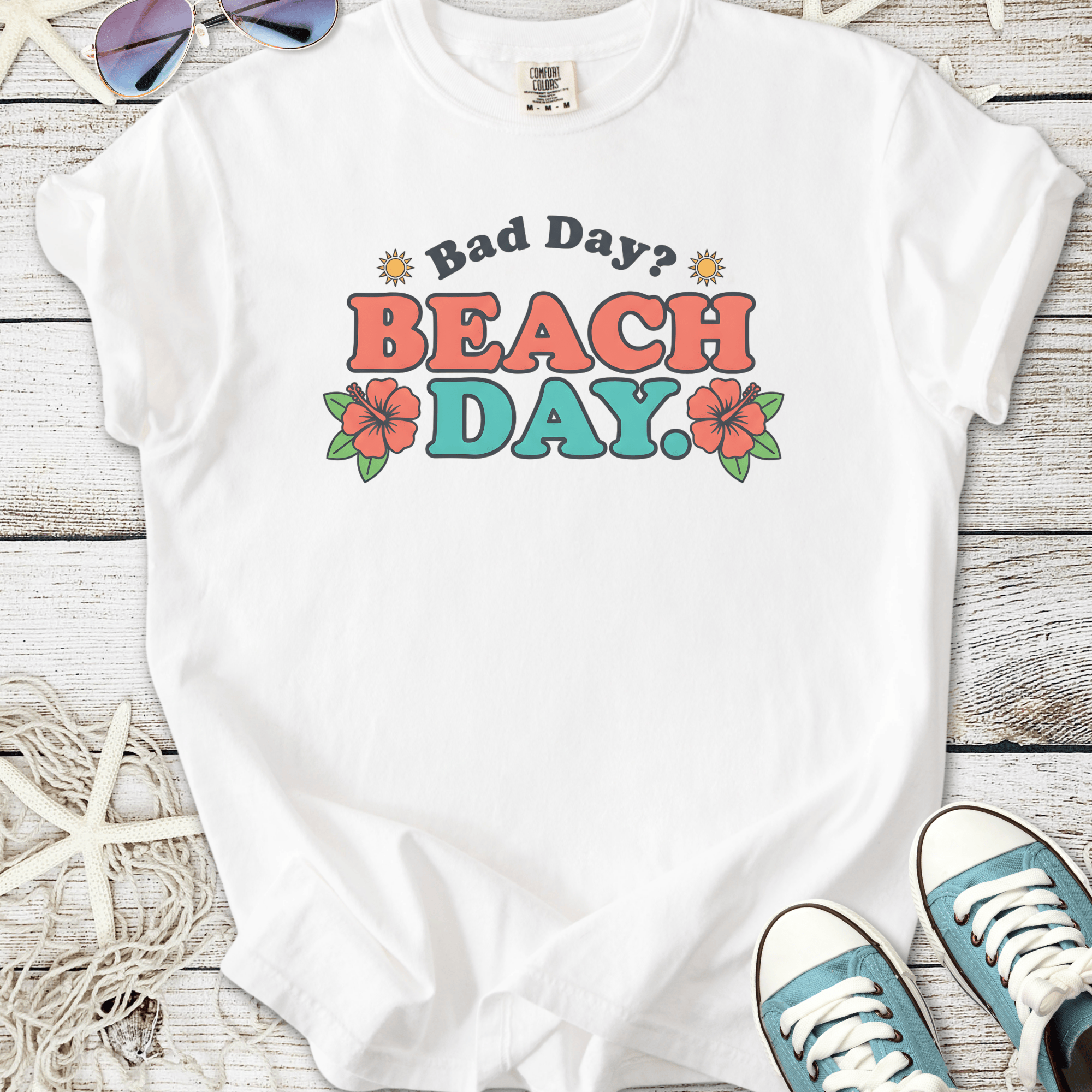 White graphic tee with 'Bad Day? BEACH DAY.' print and floral accents, perfect for summer outings.