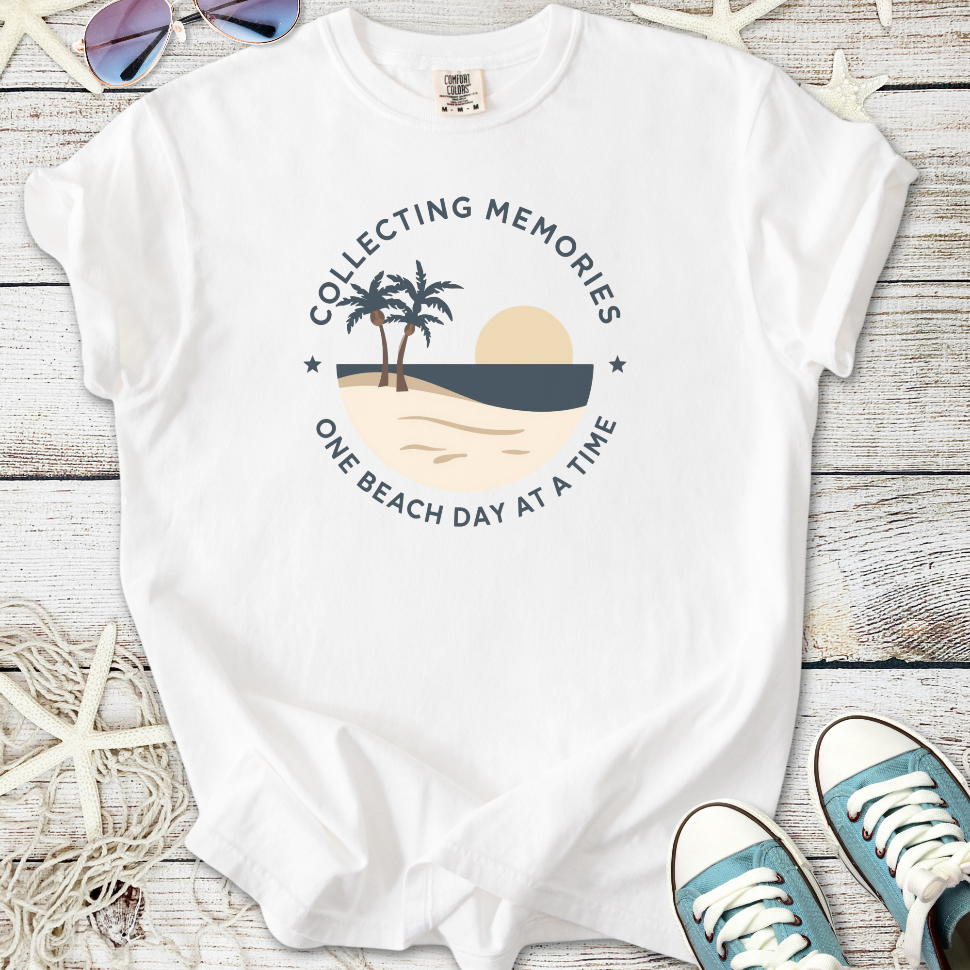 White t-shirt featuring a beach graphic and text 'Collecting Memories One Beach Day at a Time'