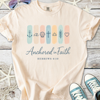 Beige t-shirt with 'Anchored in Faith' design, featuring religious symbols and Hebrews 6:19 text.