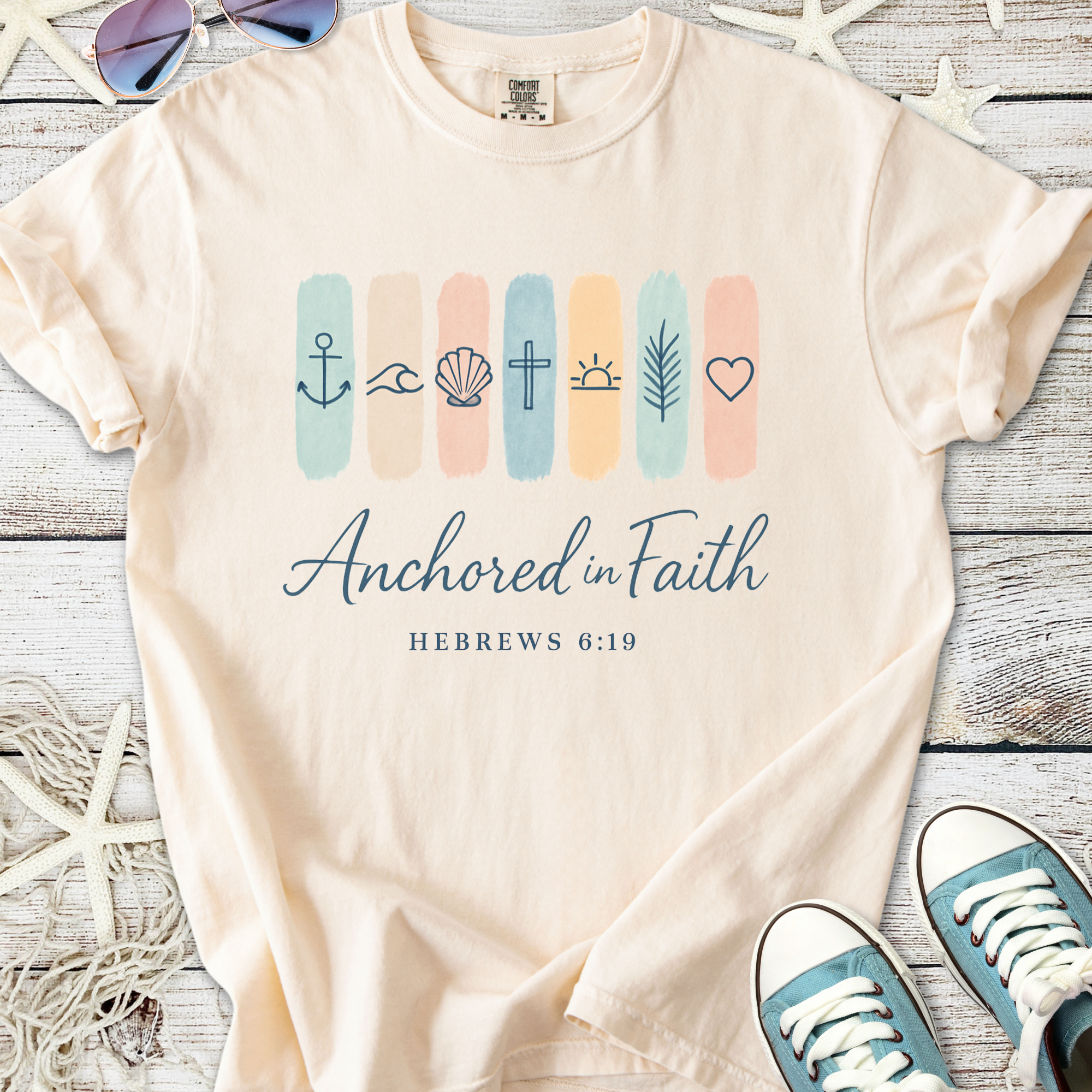 Beige t-shirt with 'Anchored in Faith' design, featuring religious symbols and Hebrews 6:19 text.