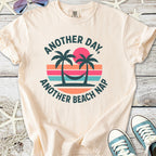 Beige graphic tee featuring palm trees and sunset design with 'Another Day, Another Beach Nap' text.