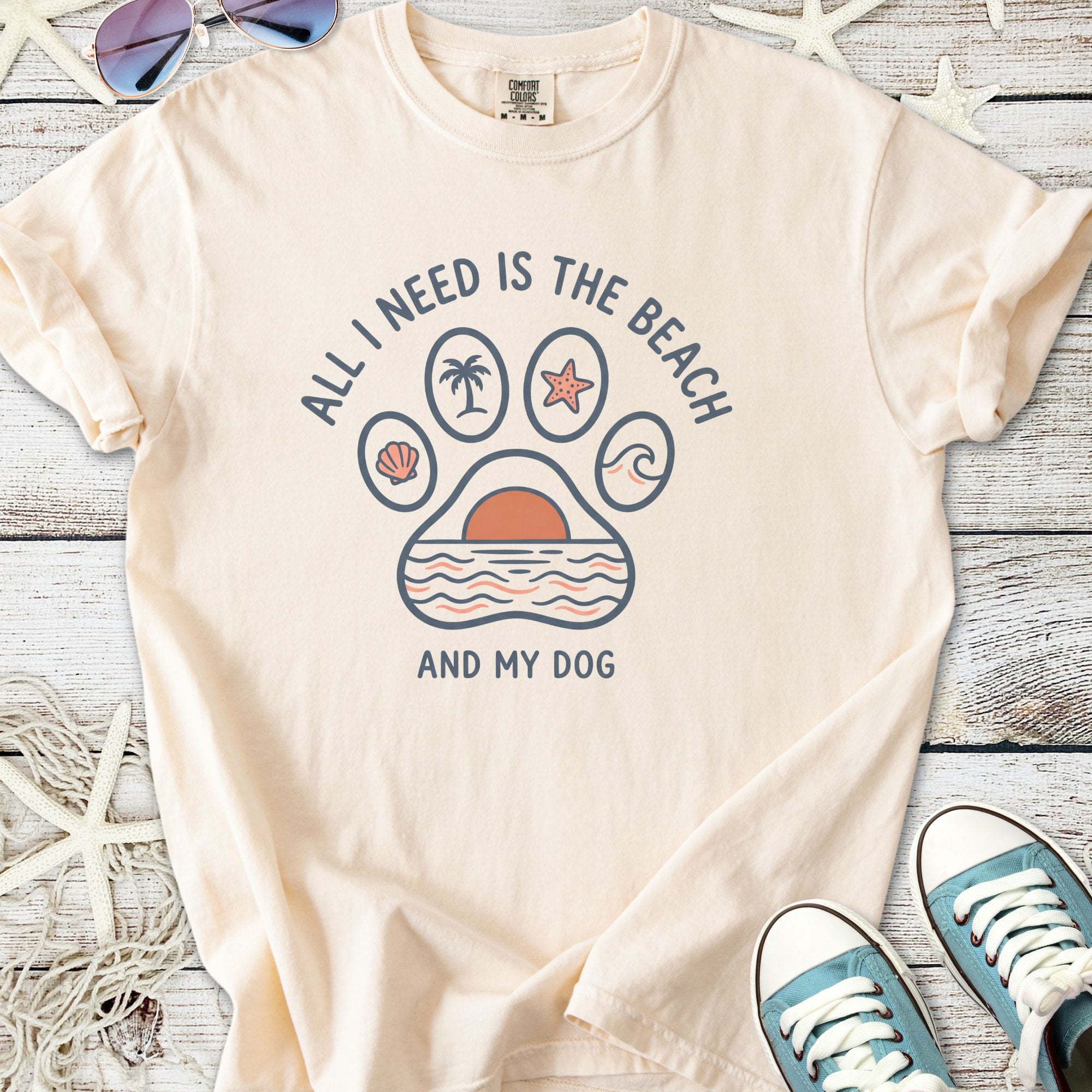 Light peach graphic tee featuring beach-themed design and text, perfect for dog lovers.