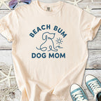 Peach beach-themed t-shirt for dog moms with 'Beach Bum Dog Mom' graphic, made from soft cotton.
