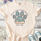 Light peach t-shirt with beach-themed paw print graphic, featuring a dog and ocean elements.