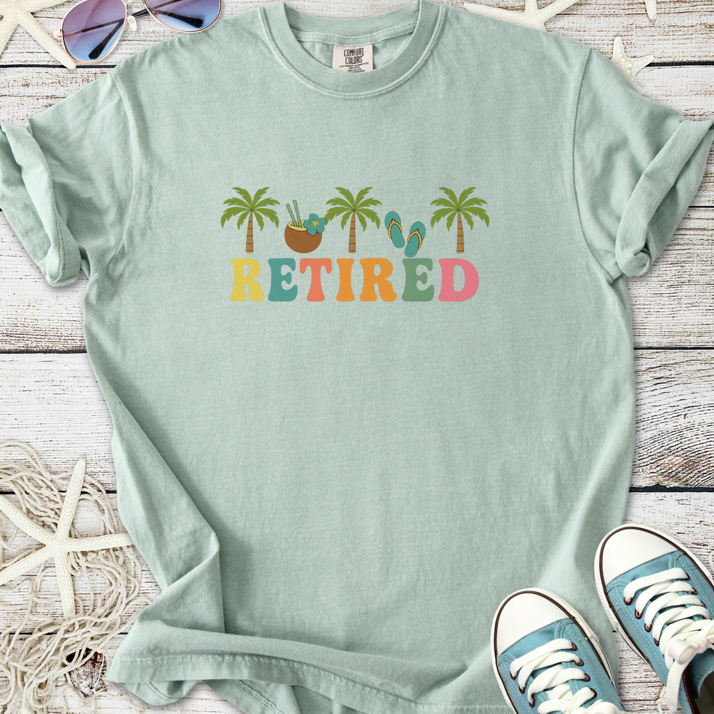 Light green 'Retired' graphic t-shirt featuring palm trees and tropical elements, perfect for casual wear.