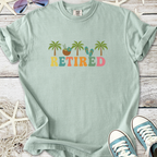 Light green 'Retired' graphic t-shirt featuring palm trees and tropical elements, perfect for casual wear.