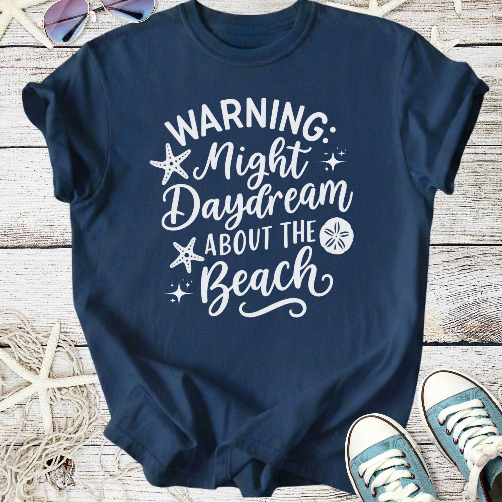 Navy blue t-shirt with 'Warning: Night Daydream About the Beach' graphic design, perfect for beach lovers.