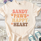 Cream graphic tee with 'Sandy Paws Happy Heart' design, featuring playful colors and fun font.