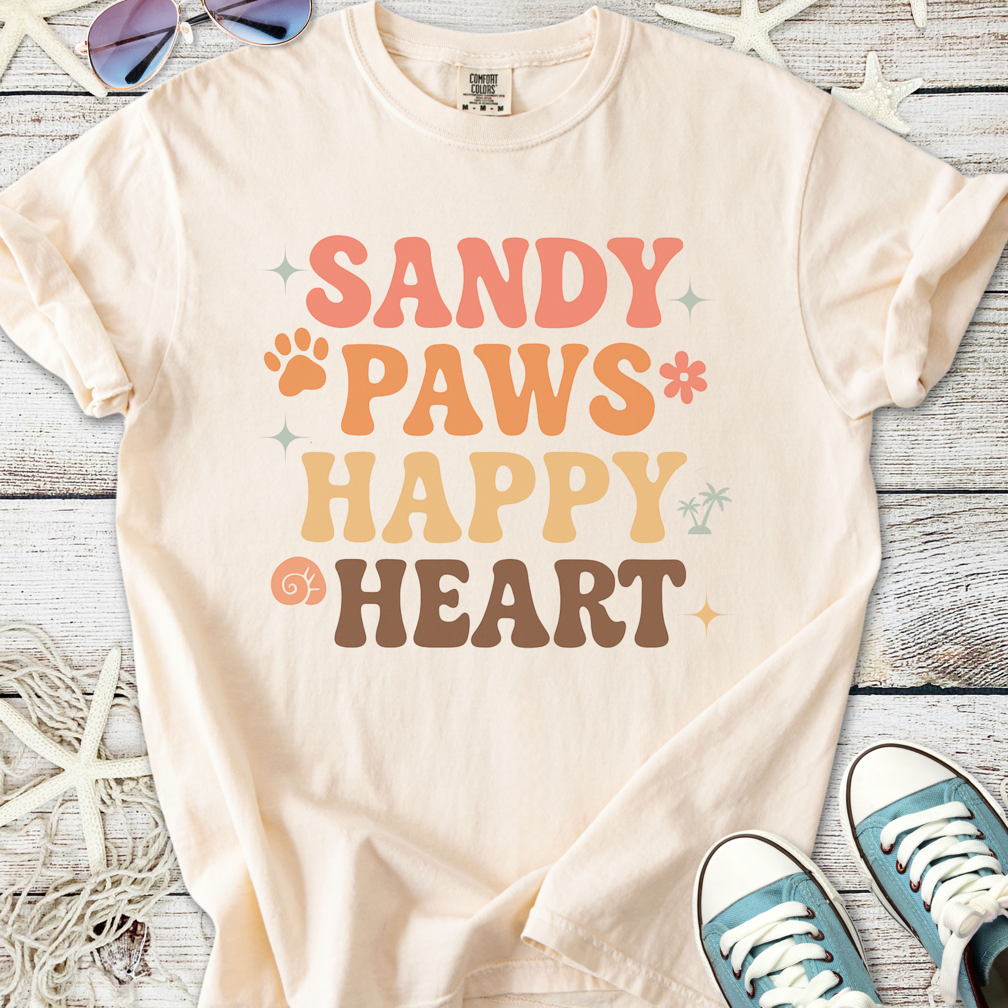 Cream graphic tee with 'Sandy Paws Happy Heart' design, featuring playful colors and fun font.