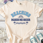 Cream t-shirt with blue graphic 'BEACHING MAKES ME NICER', perfect for summer casual wear.