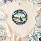 Light beige t-shirt featuring 'Beach Life Is Better With a Dog' graphic, perfect for dog lovers.