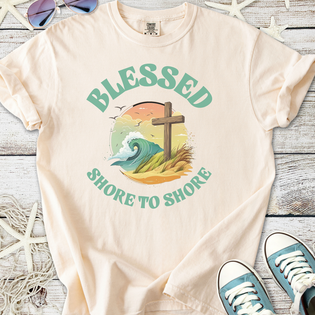 Cream graphic t-shirt featuring 'Blessed Shore to Shore' design with ocean wave and cross.
