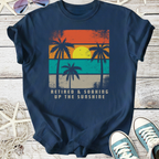 Navy blue t-shirt with retro palm tree graphic, 'Retired & Soaking Up the Sunshine' printed on front.