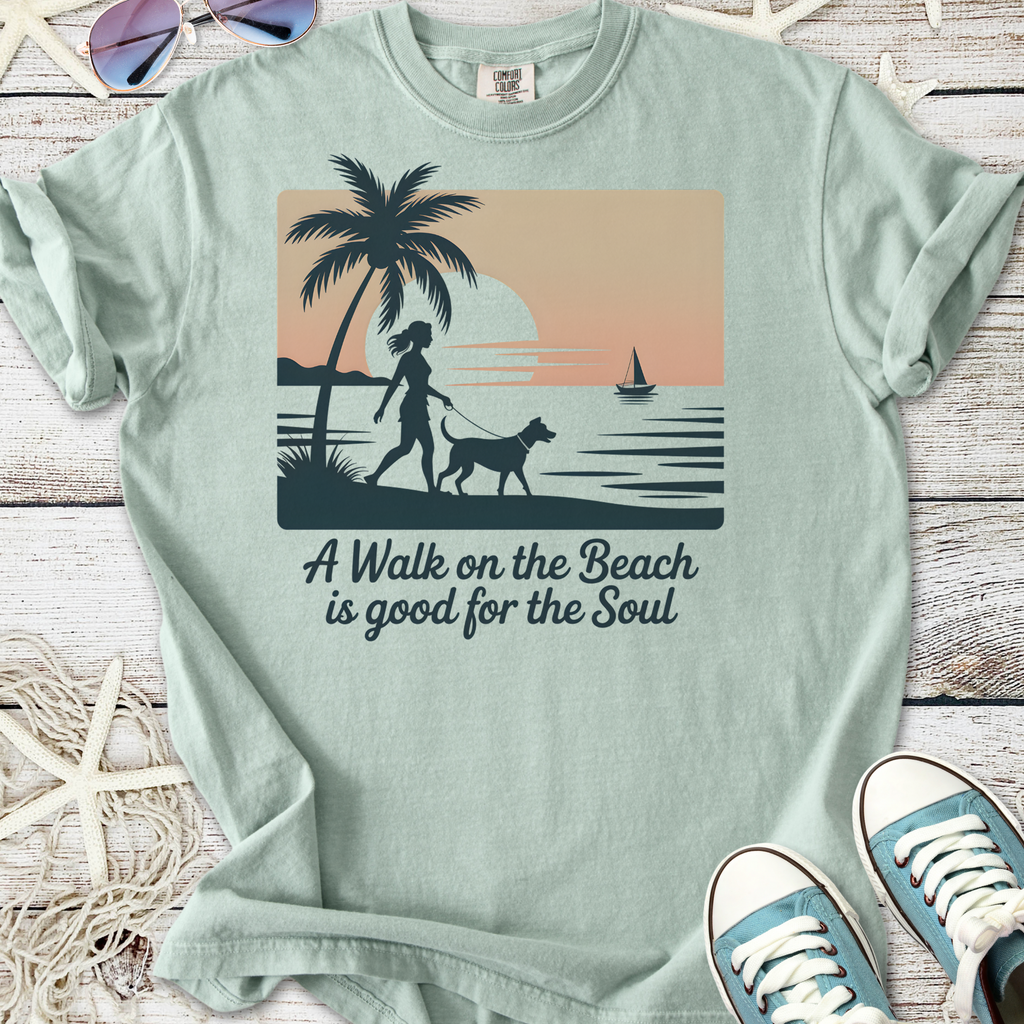 Light green t-shirt featuring beach scene graphic with a woman walking a dog and sunset design.