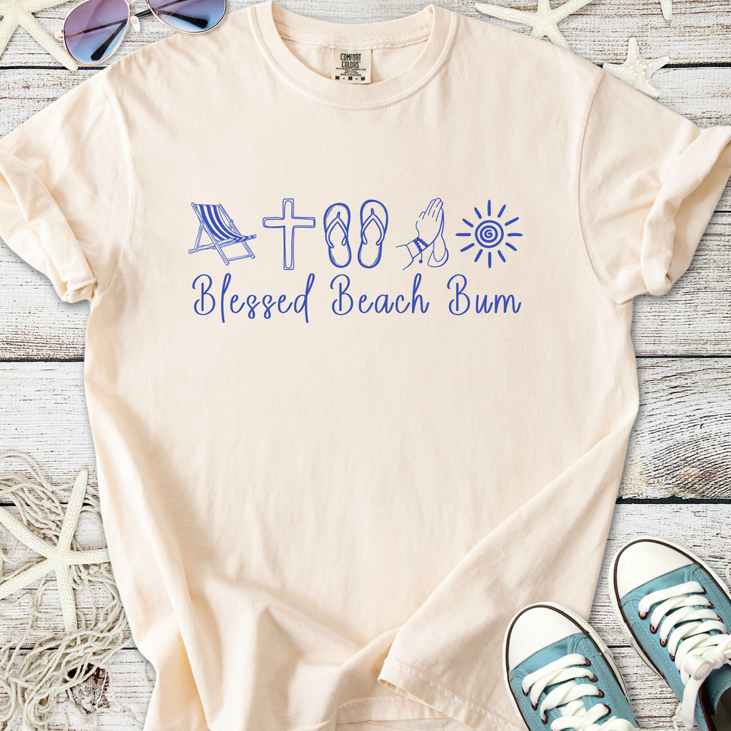 Light beige t-shirt with 'Blessed Beach Bum' graphic in blue, featuring beach icons like a chair and flip-flops.