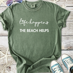 Green cotton t-shirt with 'life happens, the beach helps' text, casual beachwear style.