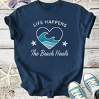 Navy blue t-shirt with 'Life Happens The Beach Heals' graphic and wave design, perfect for beach lovers.