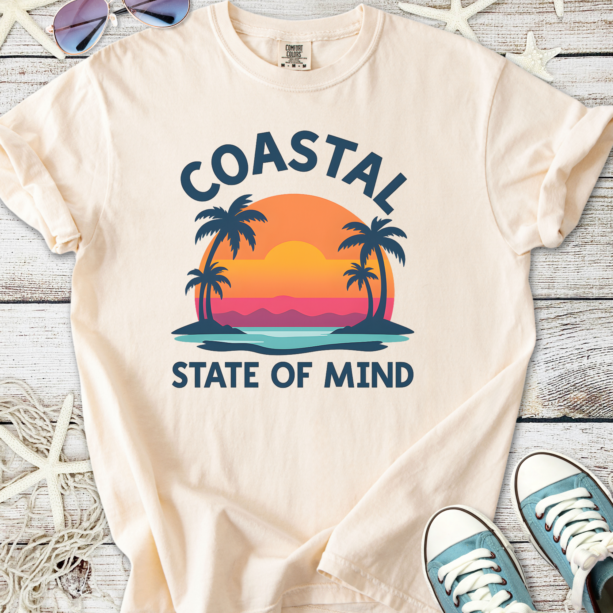 Cream coastal graphic tee featuring sunset, palm trees, and 'State of Mind' print, perfect for beach lovers.