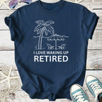 Navy blue t-shirt featuring 'I Love Waking Up Retired' graphic with palm tree and beach scene.