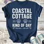 Navy blue t-shirt featuring 'Coastal Cottage Kind of Day' graphic with seashell design, perfect for beach lovers.