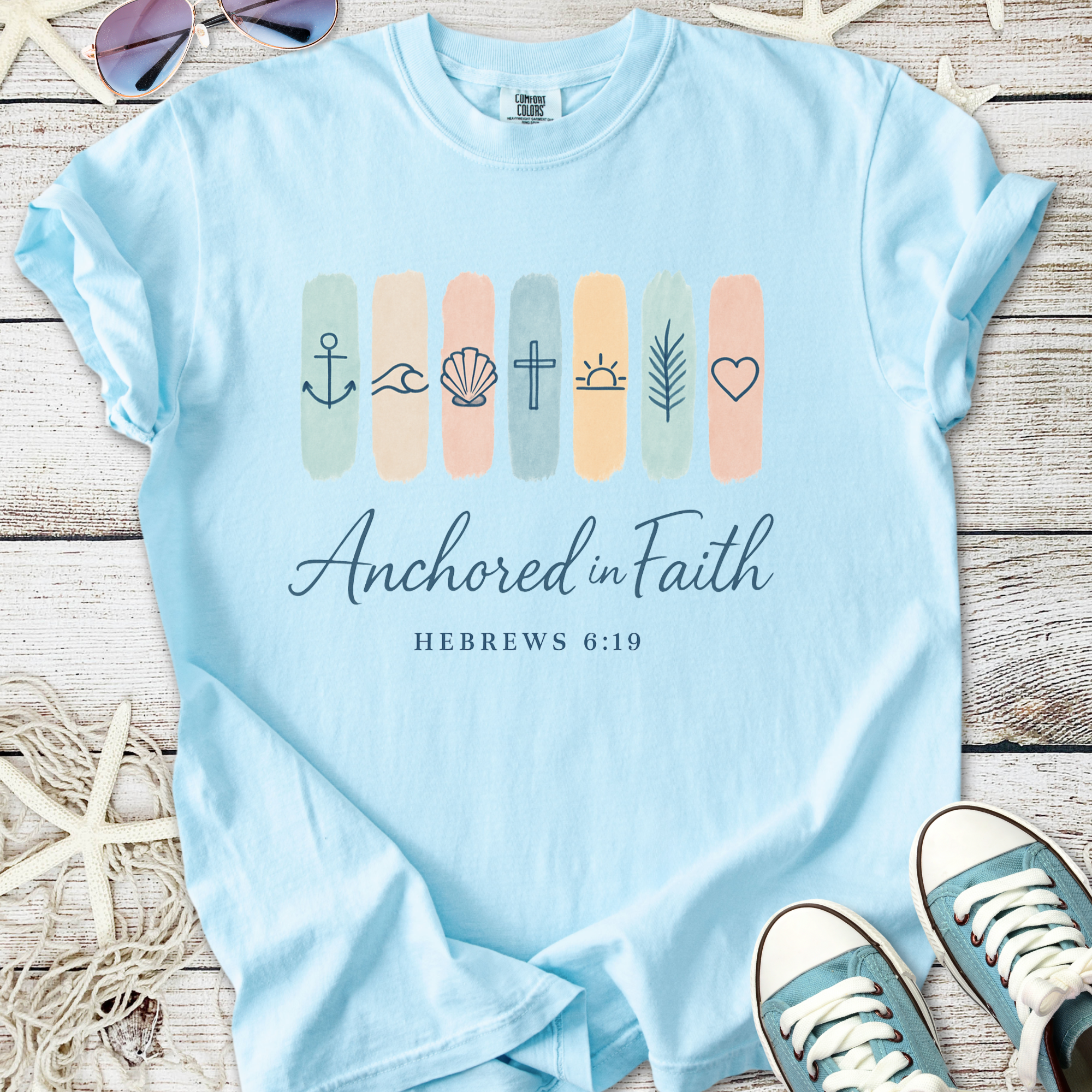 Light blue t-shirt with 'Anchored in Faith' design, featuring symbols and Hebrews 6:19, perfect for casual wear.