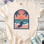 Cream t-shirt featuring a dachshund silhouette against a sunset beach scene with palm trees.