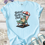 Light blue t-shirt featuring a turtle graphic with 'Retired & Turtle-y Chill' slogan, perfect for relaxing.