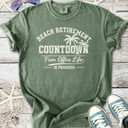 Green cotton t-shirt with 'Beach Retirement Countdown' graphic, perfect for relaxed beach vibes.