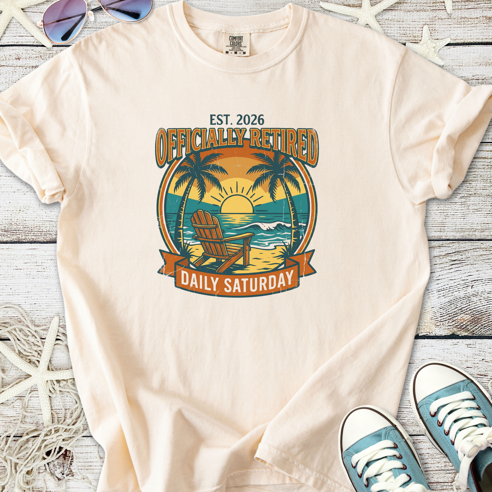 Cream t-shirt with 'Officially Retired' graphic, featuring a beach scene, perfect for casual wear.