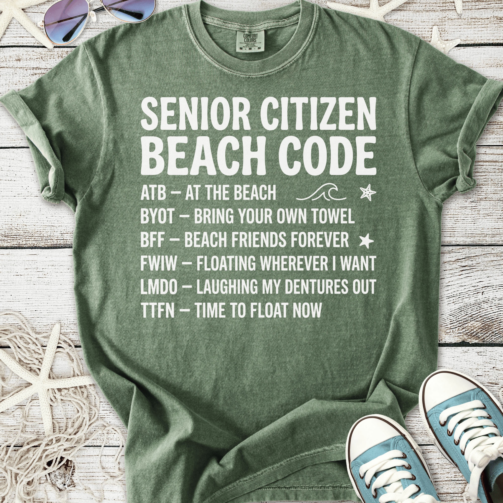 Green cotton t-shirt with 'Senior Citizen Beach Code' graphic, featuring fun beach phrases and casual style.