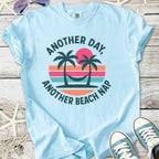 Light blue t-shirt with 'Another Day, Another Beach Nap' design featuring palm trees and sunset graphics.