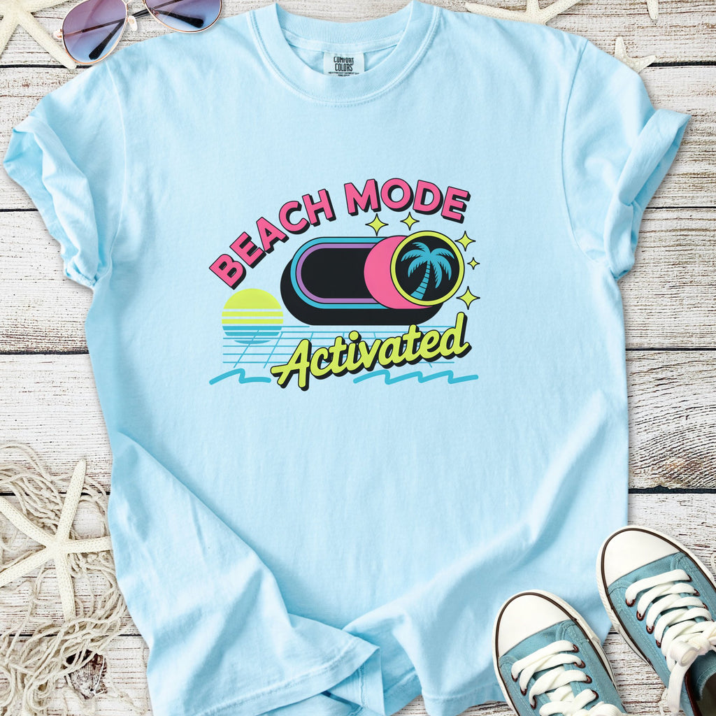 Light blue retro beach themed graphic t-shirt with sunset, palm tree button, and ‘Beach Mode Activated’ text