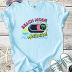 Light blue retro beach themed graphic t-shirt with sunset, palm tree button, and ‘Beach Mode Activated’ text