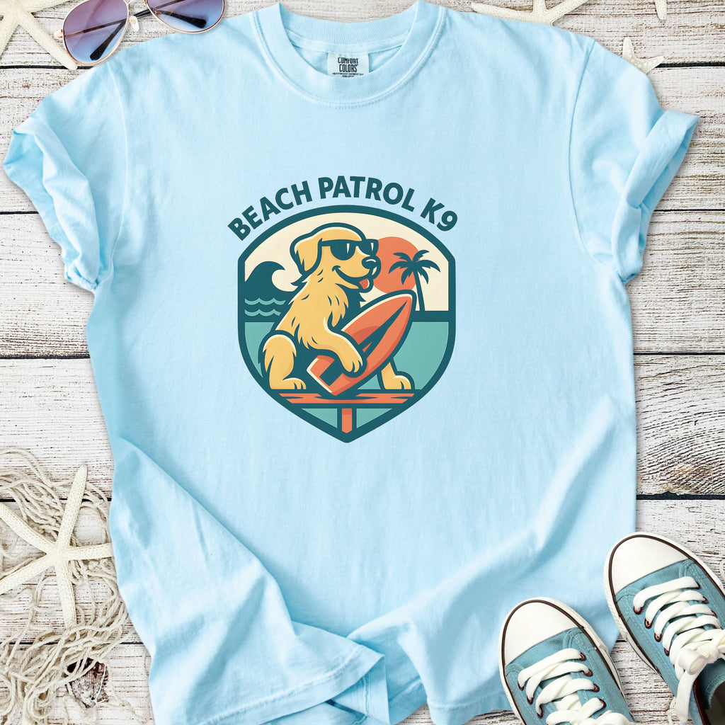 Light blue t-shirt with 'Beach Patrol K9' graphic featuring a dog on a surfboard and tropical elements.