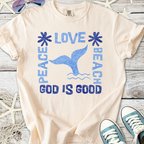 Cream beach-themed t-shirt with blue graphics: 'Peace, Love, Beach, God is Good' and a whale tail design.