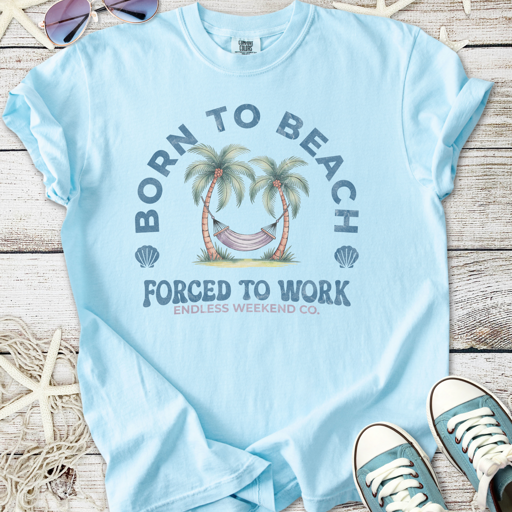 Light blue t-shirt with 'Born to Beach' graphic and hammock design, perfect for casual summer wear.