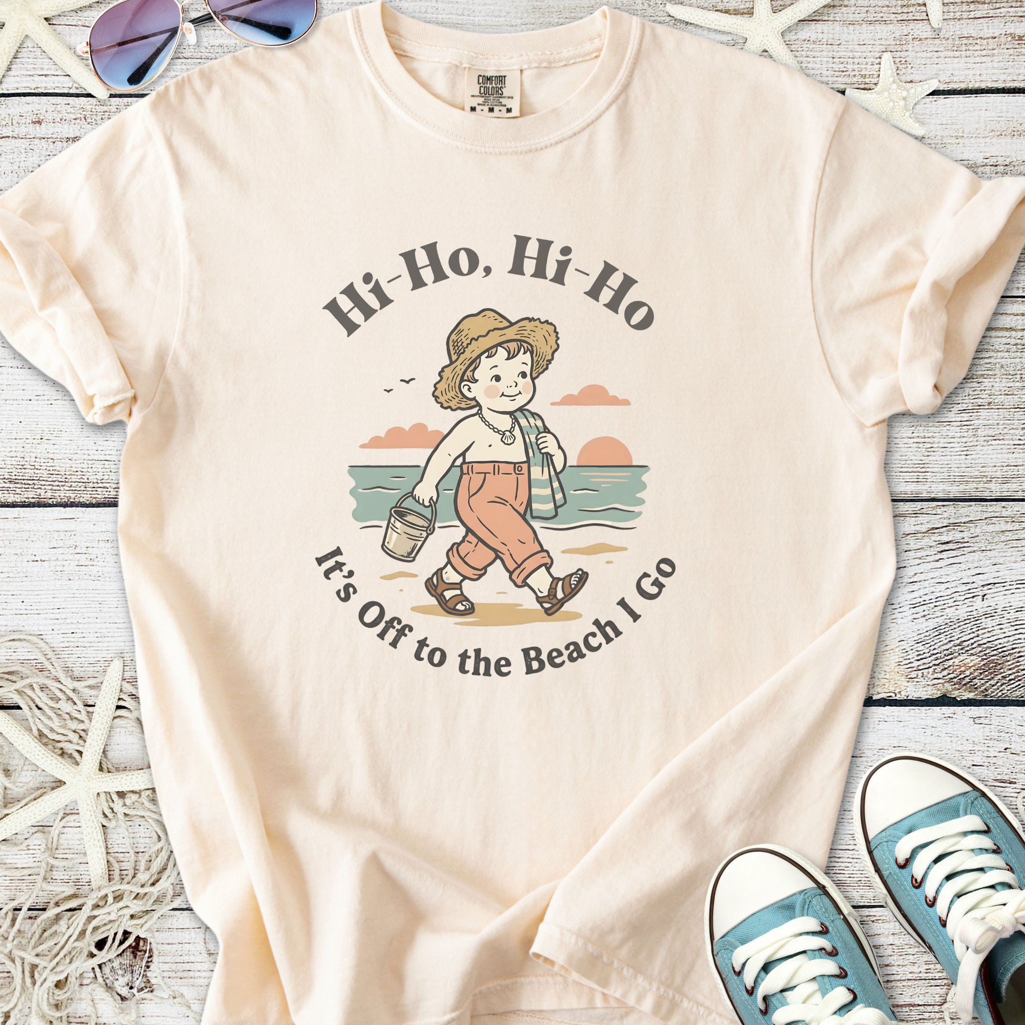 Cream beach-themed t-shirt with child graphic, cotton material, perfect for summer outings.