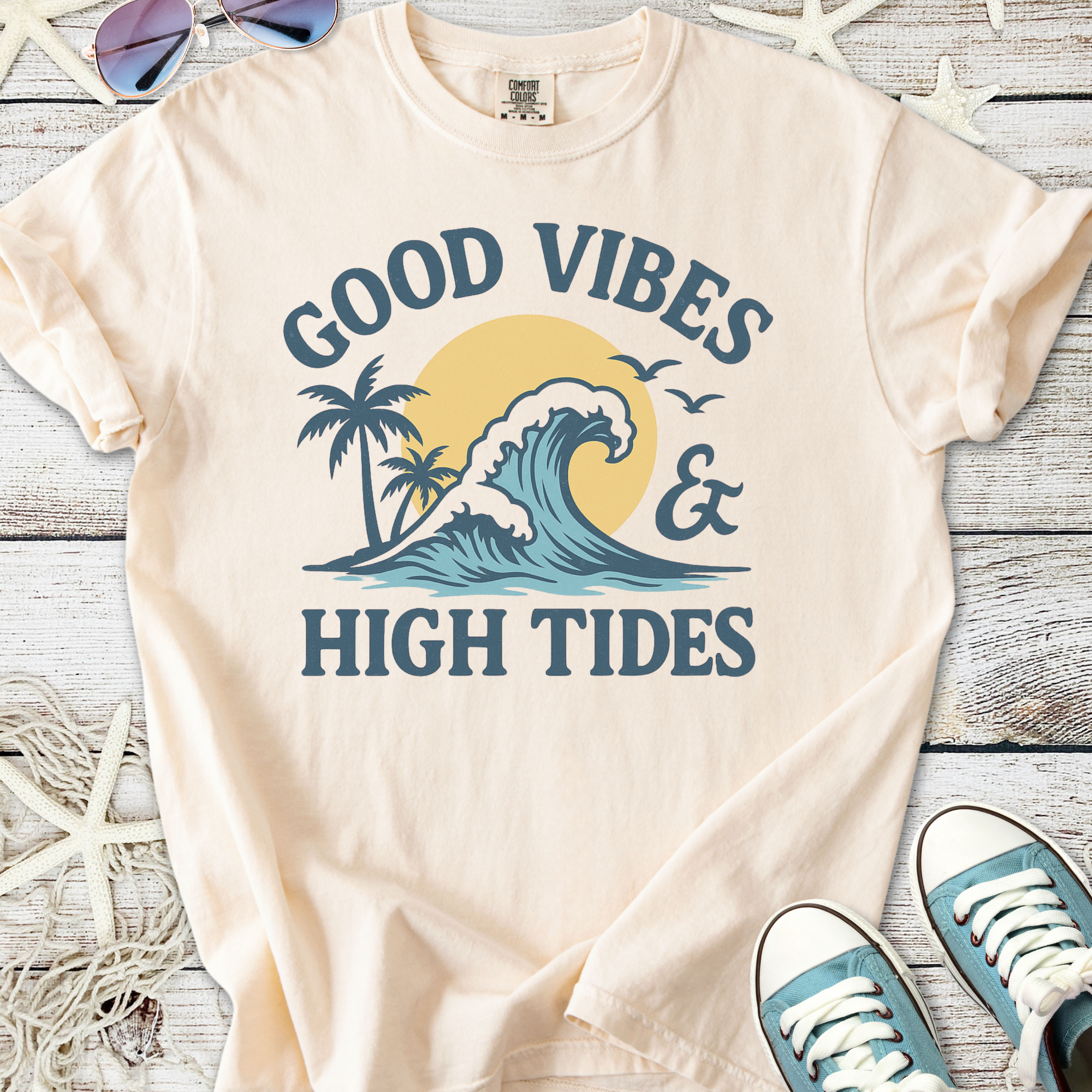 Cream t-shirt with 'Good Vibes & High Tides' graphic, featuring a wave and palm trees, perfect for beach lovers.