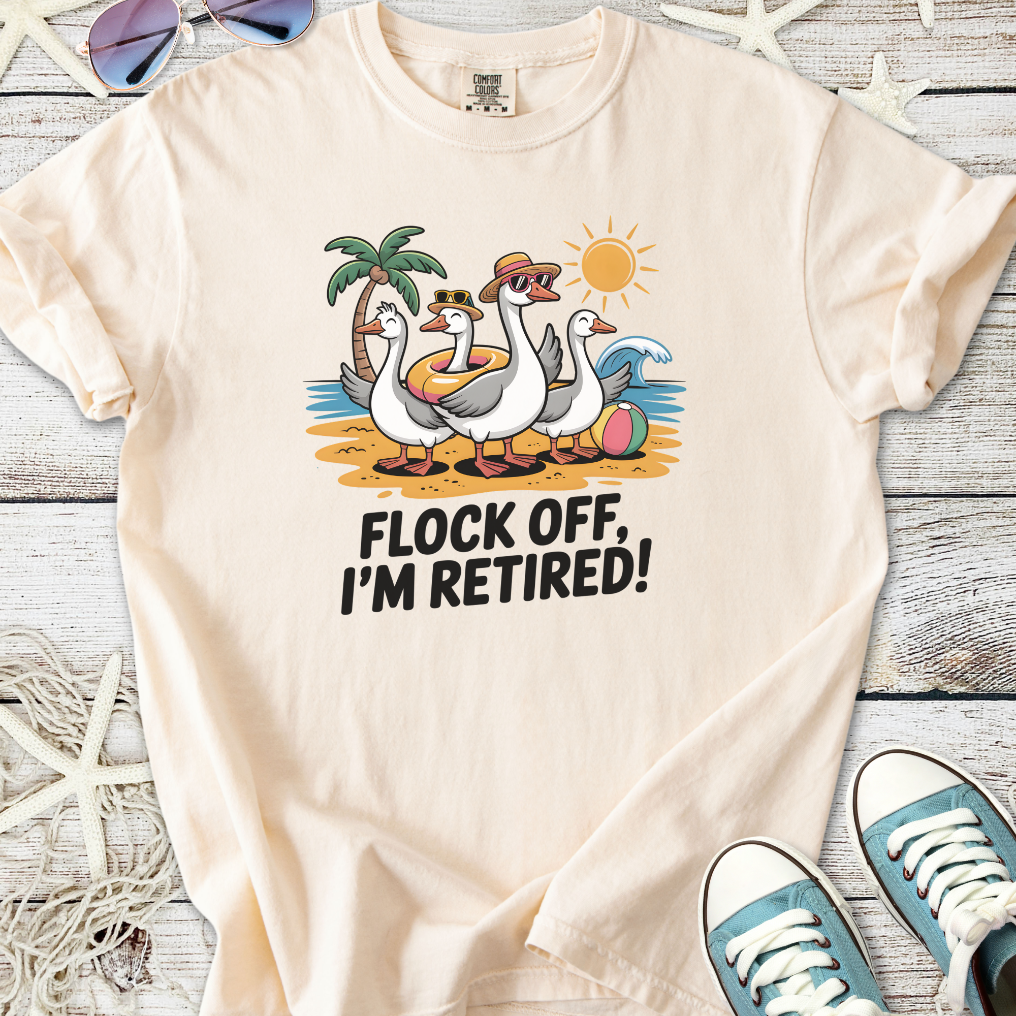 Cream t-shirt with quirky 'Flock Off, I'm Retired!' graphic featuring cartoon ducks at the beach.