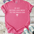 Pink cotton graphic tee with 'In My Retire and Move to the Beach Era' text and palm tree design.