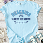 Light blue t-shirt with 'Beaching Makes Me Nicer' print, perfect for summer beach outings.