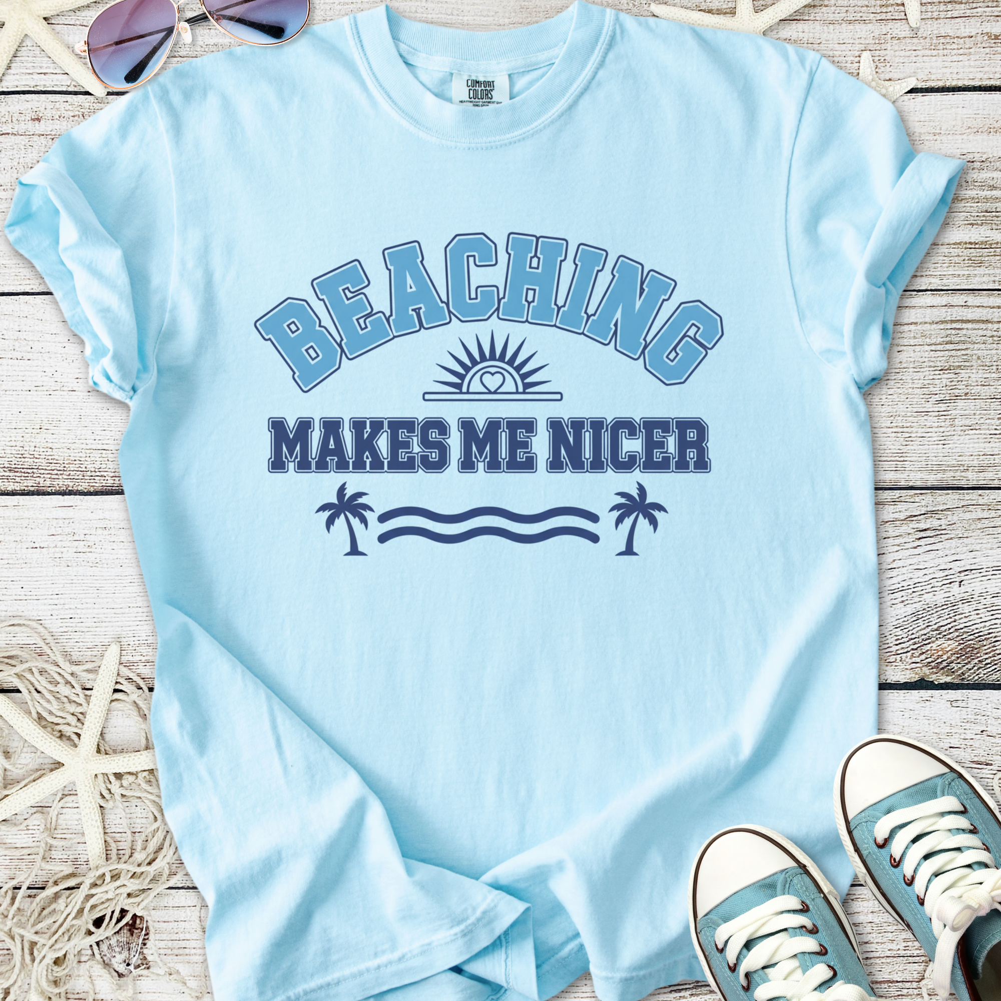 Light blue t-shirt with 'Beaching Makes Me Nicer' print, perfect for summer beach outings.
