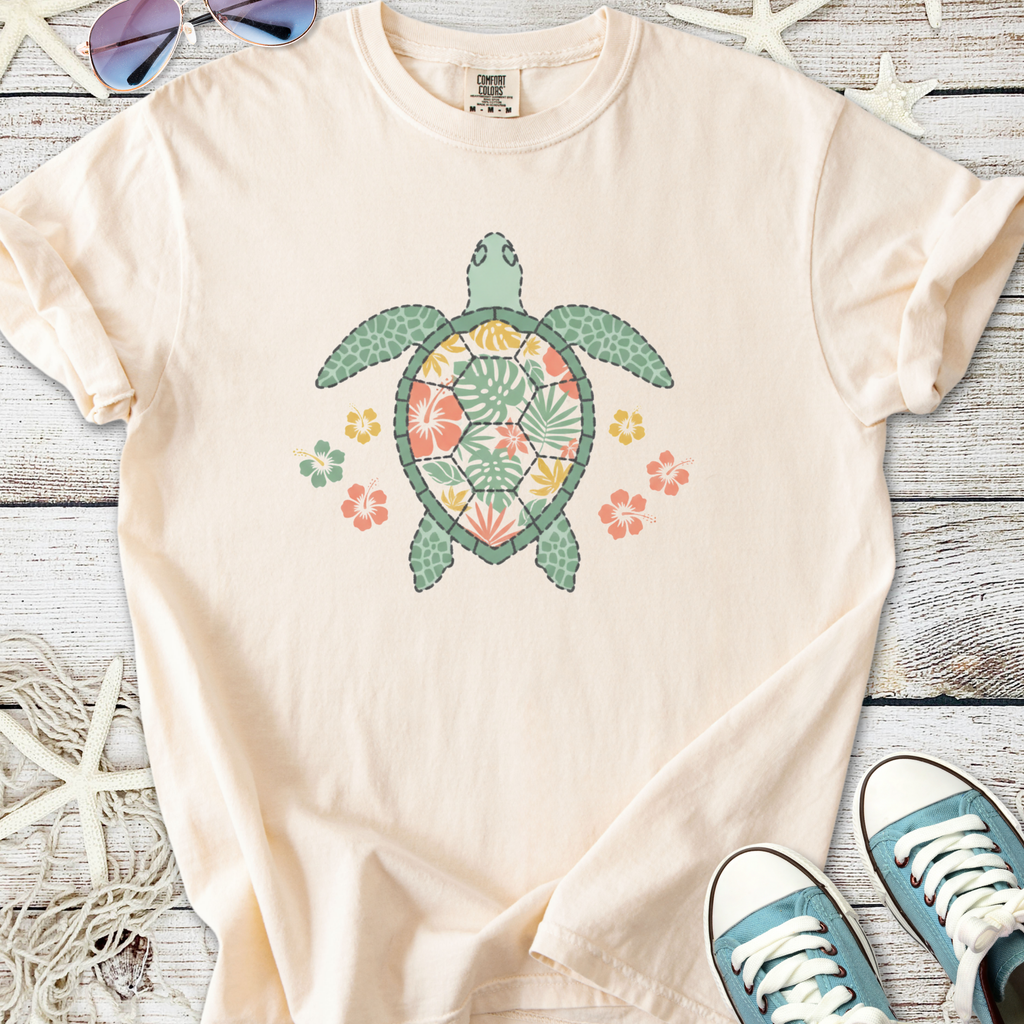 Light peach t-shirt featuring a colorful turtle and floral design, made from soft cotton material.