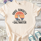 Cream t-shirt featuring a dog silhouette, sunset design, and text 'Dogs, Sunsets & Saltwater'.