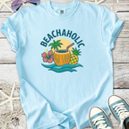 Light blue Beachaholic t-shirt featuring a tropical drink graphic with palm trees and hibiscus flower.